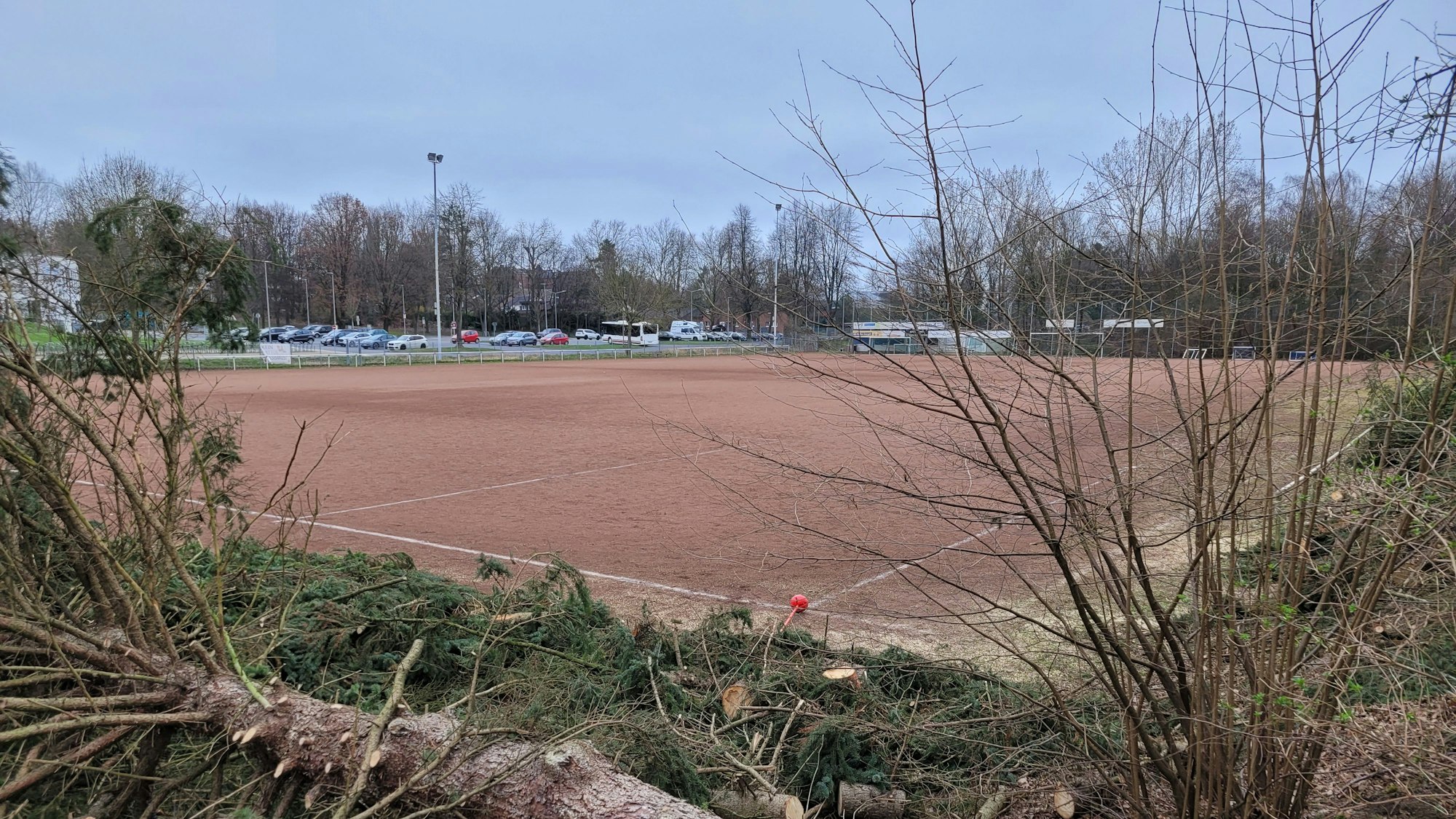 Ein Aschenplatz, im Hintergrund parkende Autos.