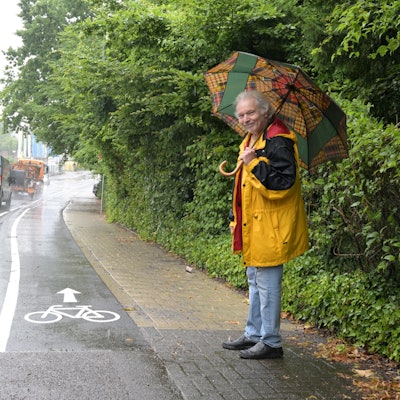 Zu sehen sind die Markierungen des neuen Radwegs. Der Anwohner steht daneben auf dem Bürgersteig.