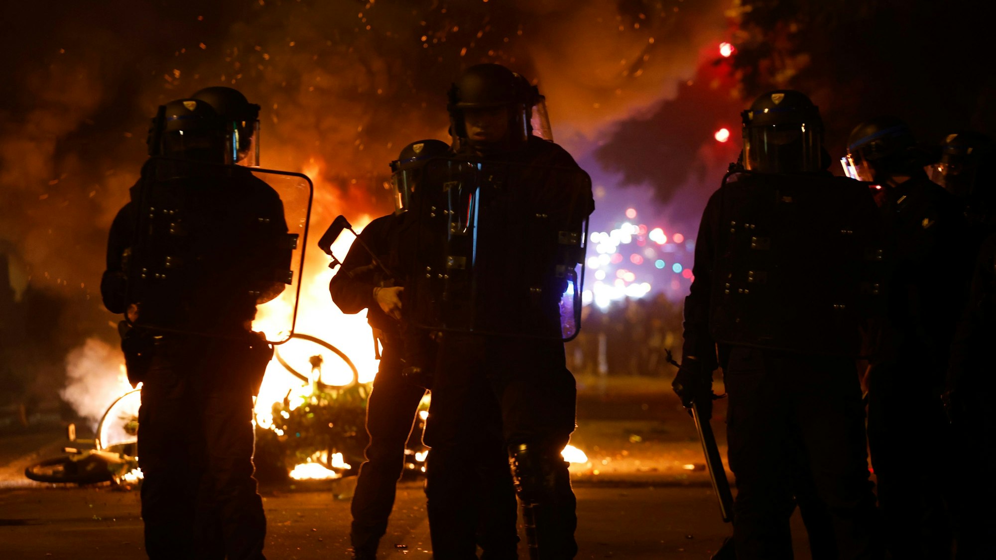 Frankreich, Paris: Polizisten stehen bei brennenden Fahrrädern während der Spannungen in der Nähe des Platzes der Republik nach der zweiten Runde der Parlamentswahlen in Paris.