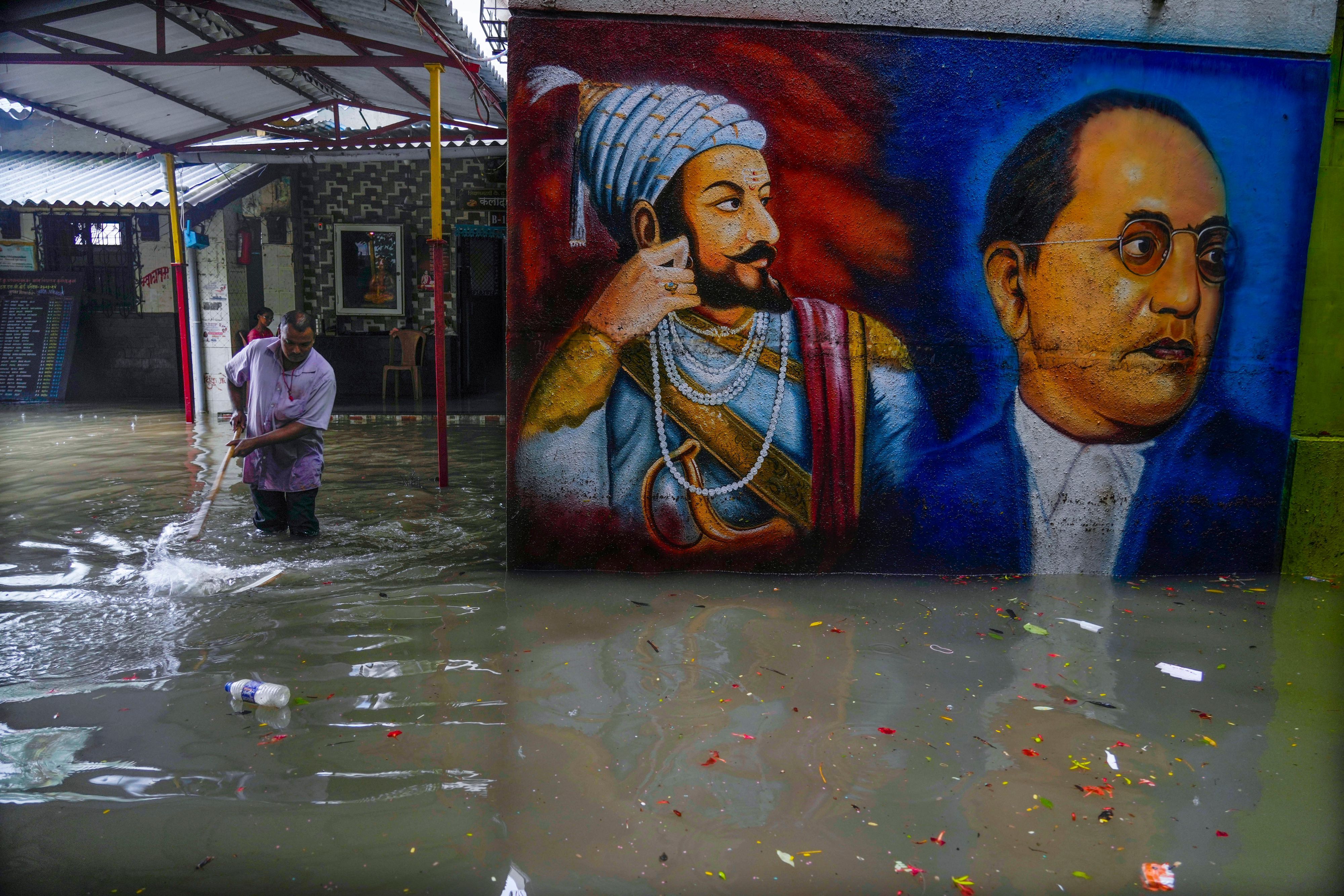 Ein Mann versucht nach schweren Regenfällen in Mumbai, dass Wasser auf einem Schulgelände abläuft.