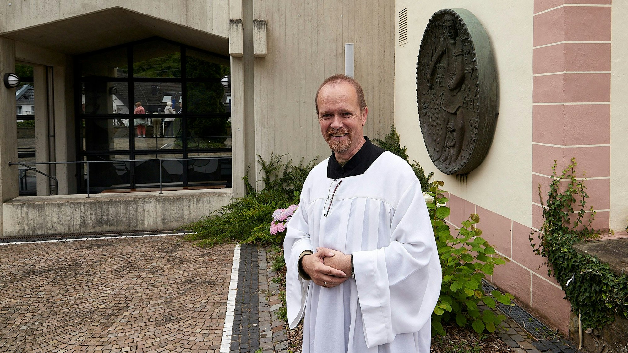 Markus Lang trägt ein Messdienergewand und steht vor der Kirche in Heimbach, um die Pilger zu empfangen.
