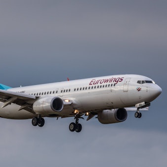 Eine Boeing 737 der deutschen Fluggesellschaft Eurowings im Landeanflug vor einem Unwetter. Am Flugzeug leuchten mehrere Warnleuchten. (Symbolbild)