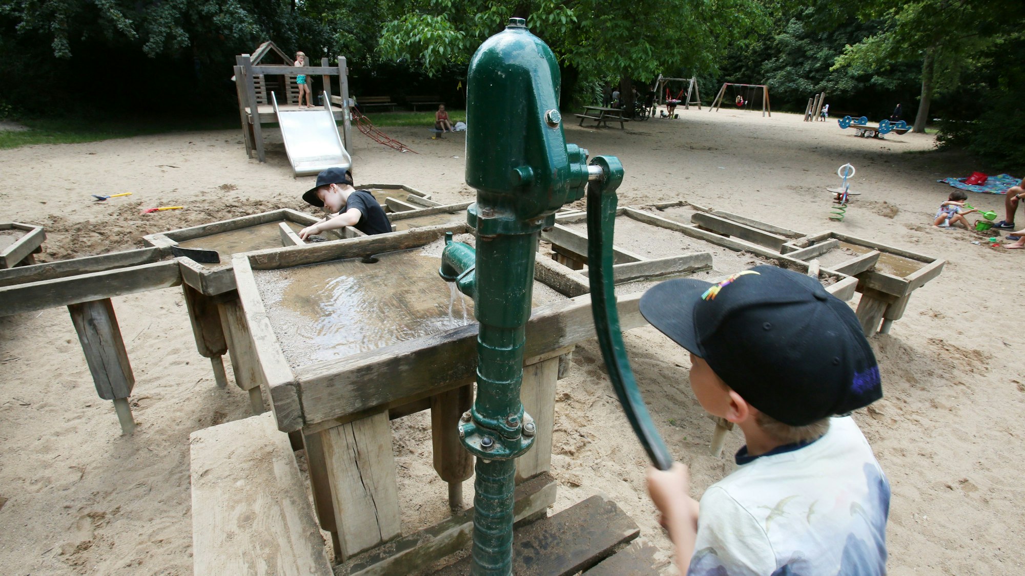 Ein kleiner Junge bedient die Wasserpumpe am Wasserspielplatz im Nippeser Tälchen.