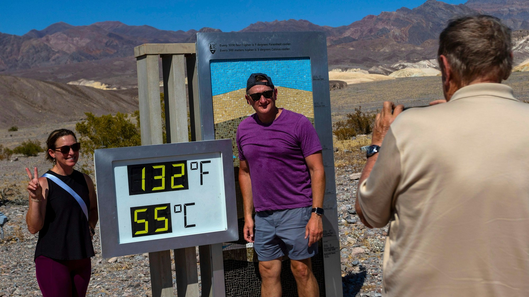 Melissa Bolding und Bryan Bolding aus Oklahoma City posieren für ein Bild neben einem Thermometer, das eine Temperatur von 132 Grad Fahrenheit / 55 Grad Celsius im Furnace Creek Visitors Center im Death Valley National Park in Kalifornien anzeigt.