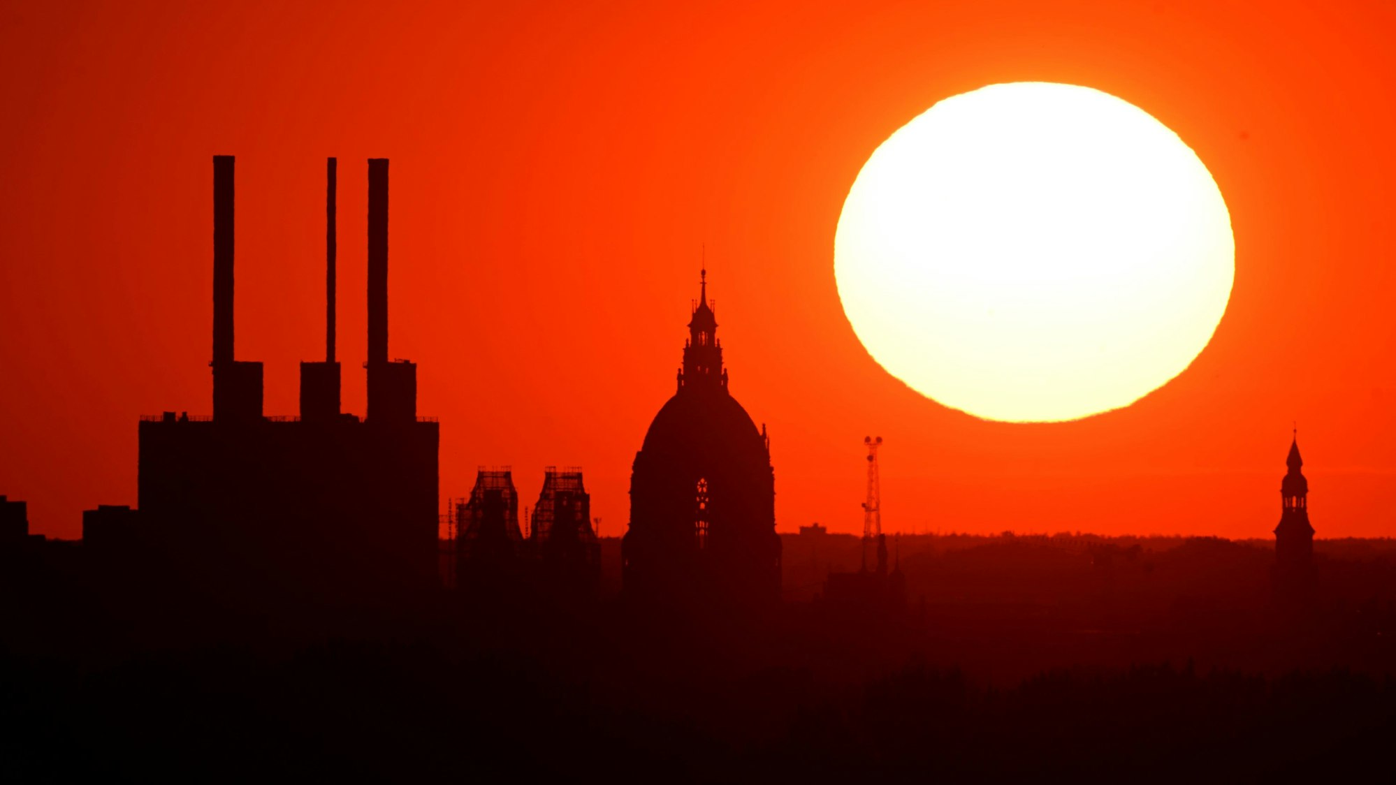 Die Sonne geht hinter einem Kraftwerk an einem leuchtend roten Himmel unter. In Europa werden ab Dienstag (8. Juli) extreme Temperaturen erwartet. (Symbolbild)
