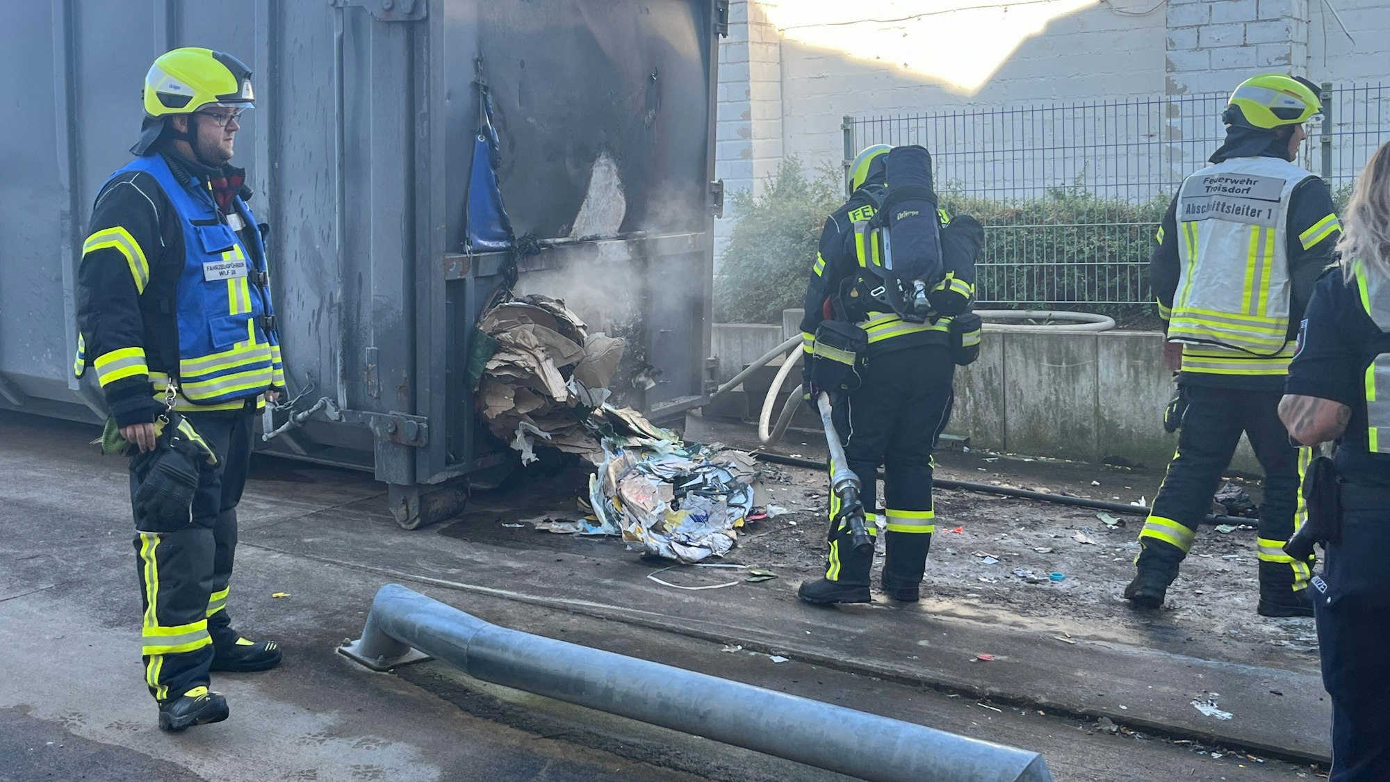 Einsatzkräfte löschen die gepressten Papier- und Pappbündel aus dem Container.