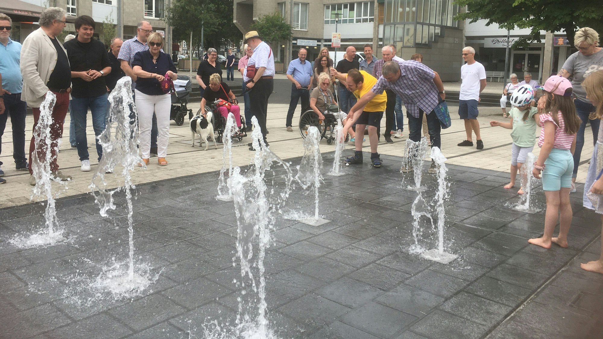 Aus mehreren Löchern im Marktplatzboden sprudeln Wasserfontänen hoch.
