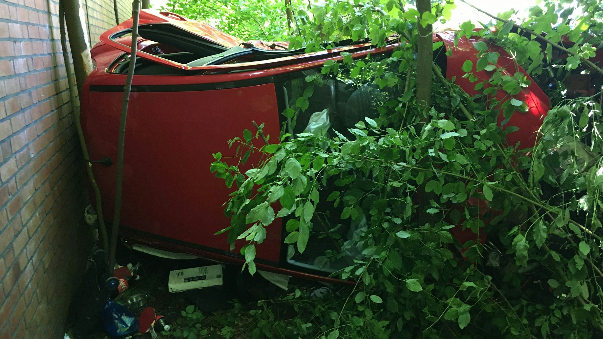 Ein Auto liegt an einer Gebäudewand auf der Beifahrerseite.