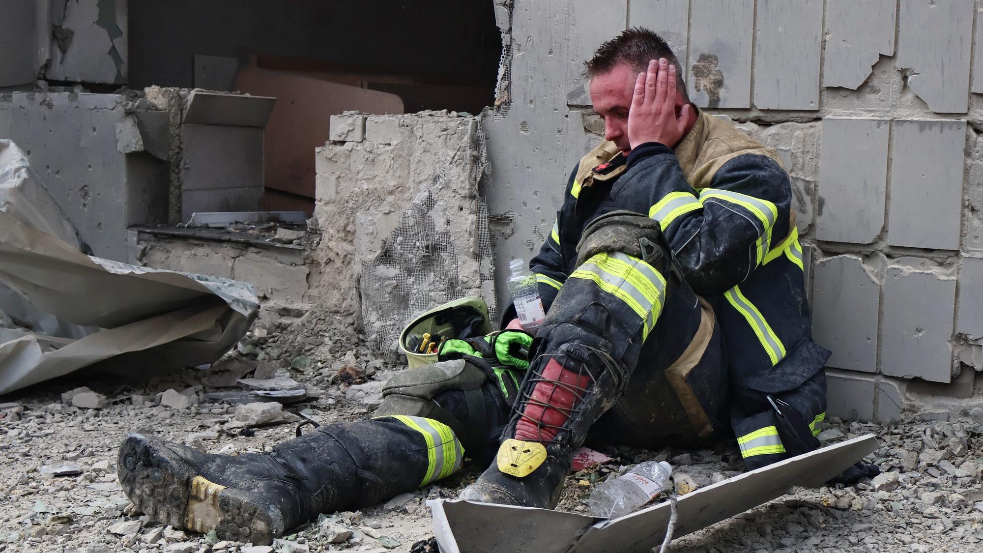 Ein Feuerwehrmann sitzt erschöpft in der Nähe der Kinderklinik, die durch einen Raketenangriff beschädigt wurde.