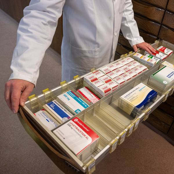 Ein Apotheker schaut in den Medikamentenschrank seiner Apotheke.