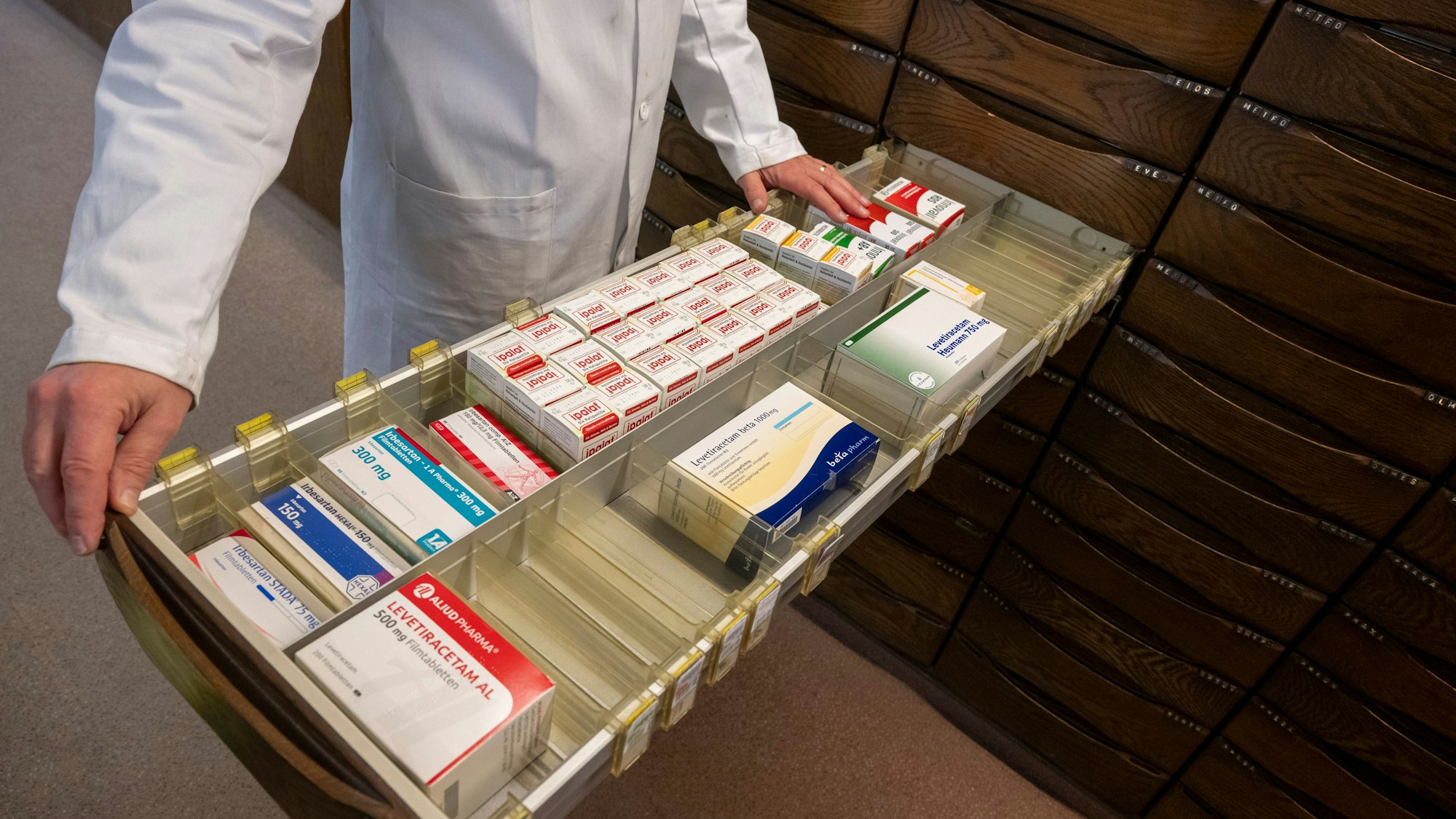 Ein Apotheker schaut in den Medikamentenschrank seiner Apotheke.