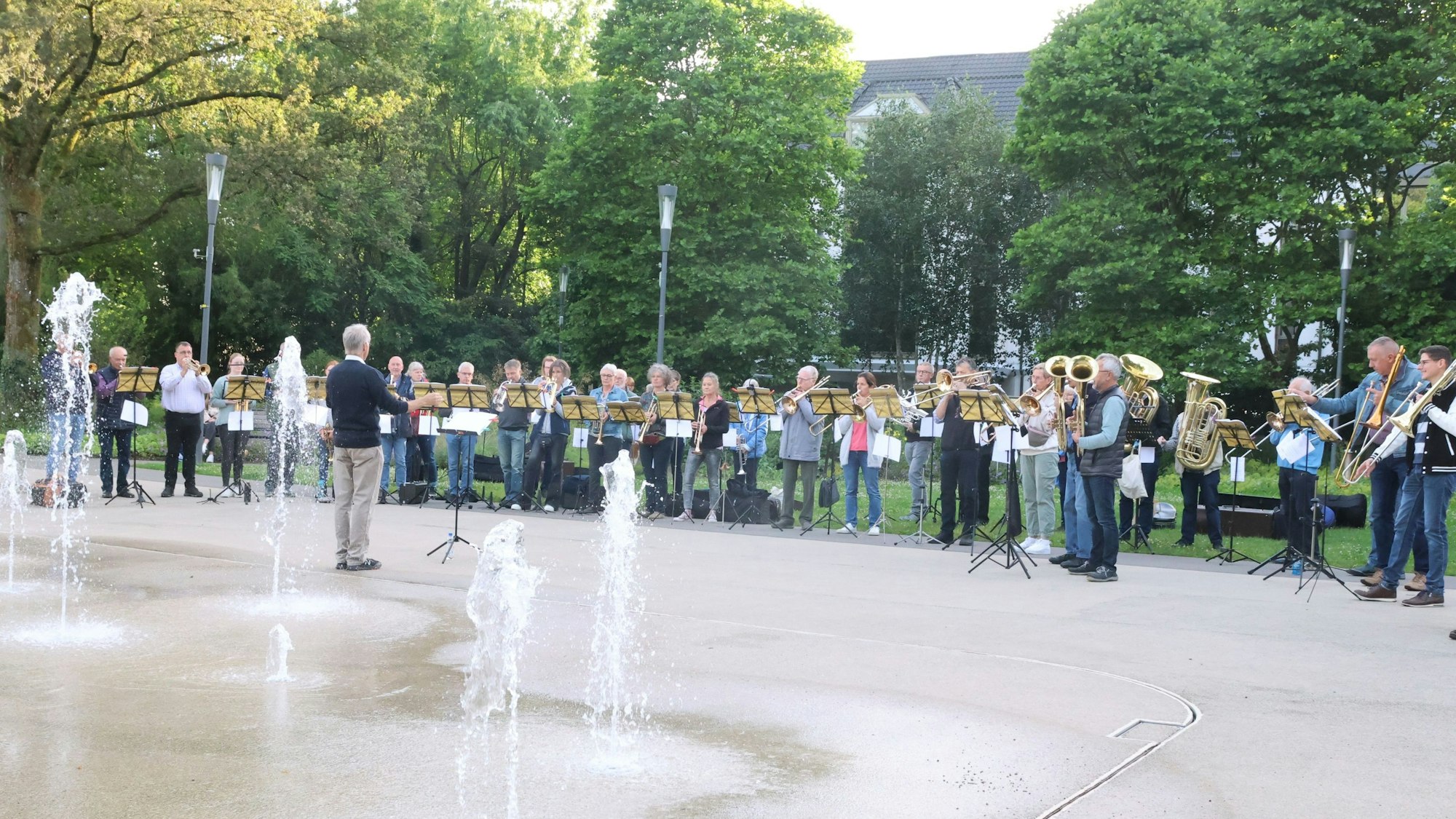 Ein Blasorchester spielt, im Vordergrund sieht man ein Wasserspiel.