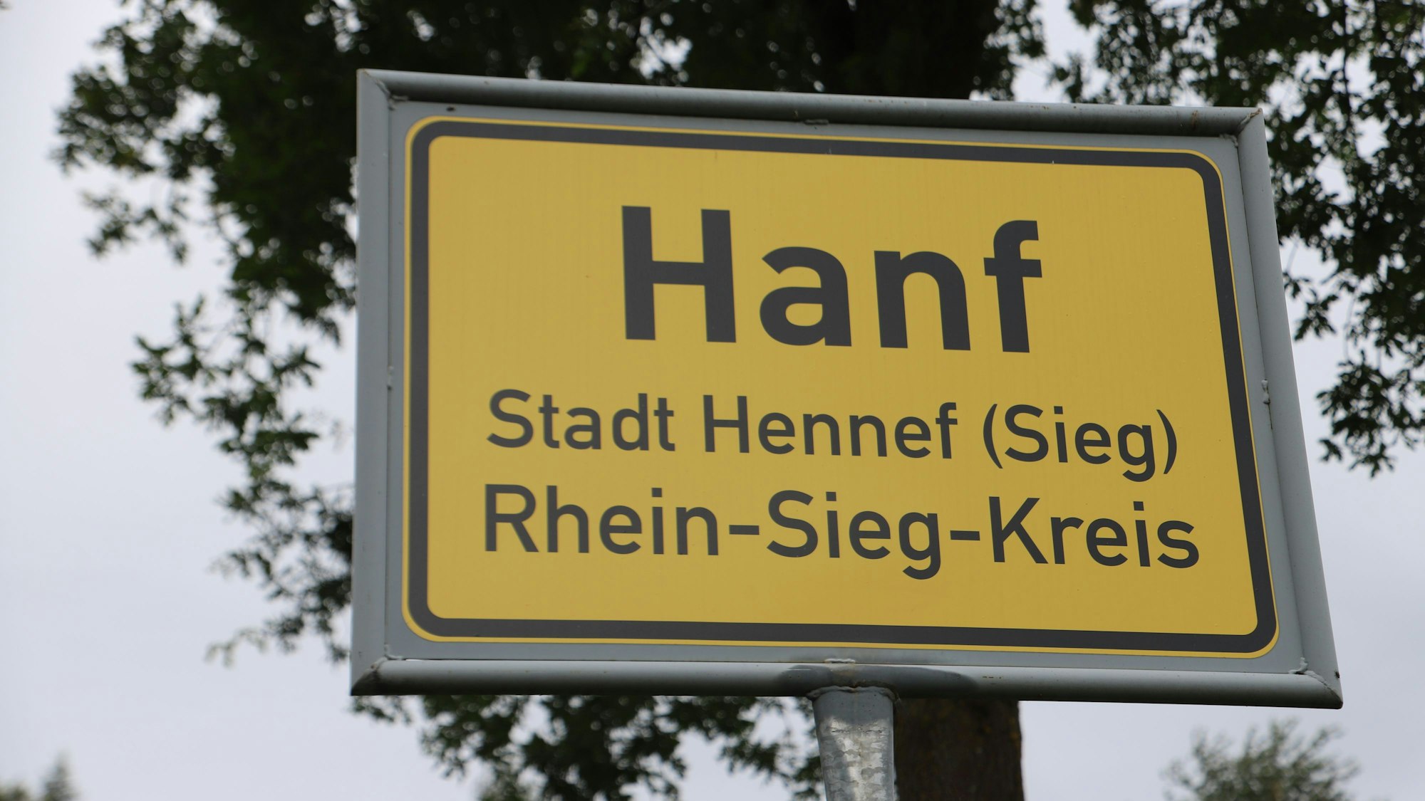 Auf einem gelben Ortseingangsschild steht Hanf, Stadt Hennef (Sieg), Rhein-Sieg-Kreis.