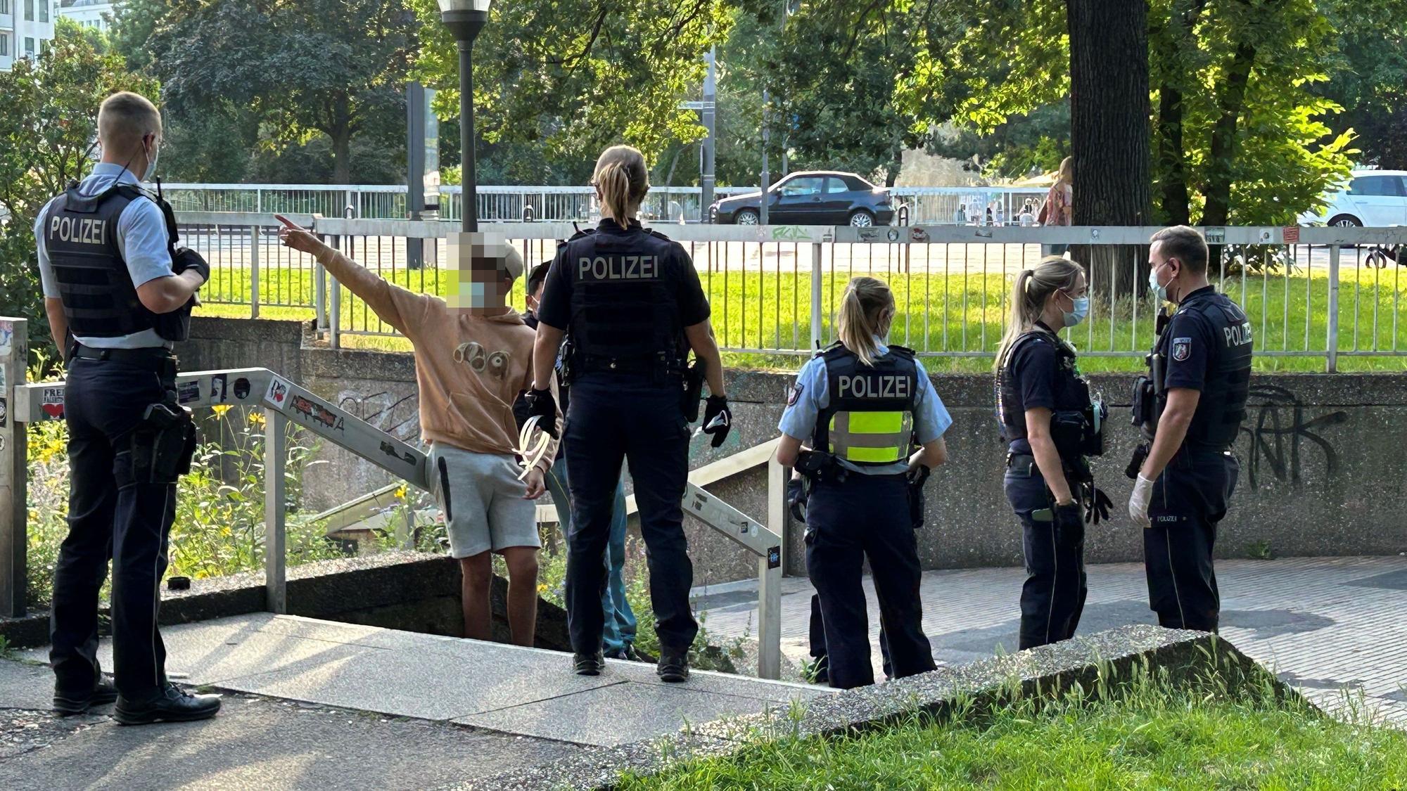 Mehrere Polizisten stehen an einer Treppe am Ebertplatz und unterhalten sich mit einem jungen Mann.