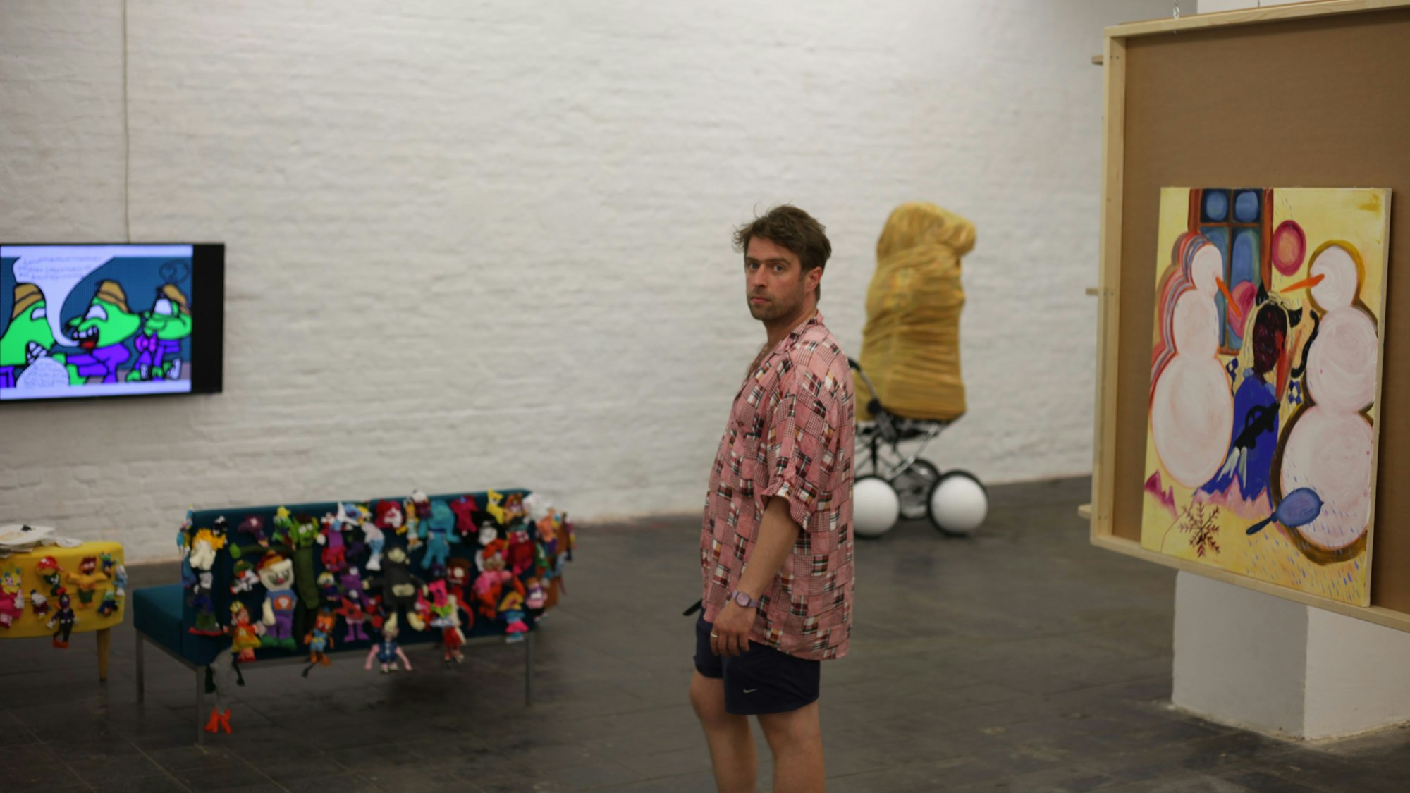 Kurator Camillo Grewe inmitten mehrerer der ausgestellten Kunstwerke.