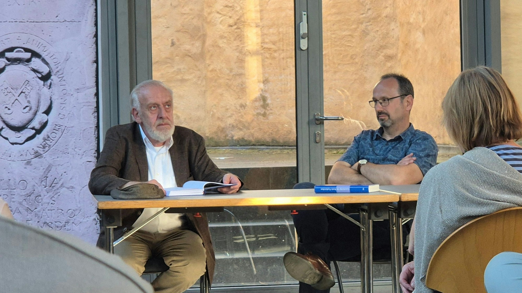 Bernhard Wißmann und Hans-Gerd Dick sitzen nebeneinander an einem Tisch, vor ihnen Publikum.