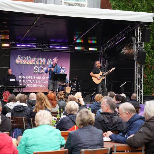 Eine Band steht auf der Freilichtbühne am Hürther Bürgerhaus.
