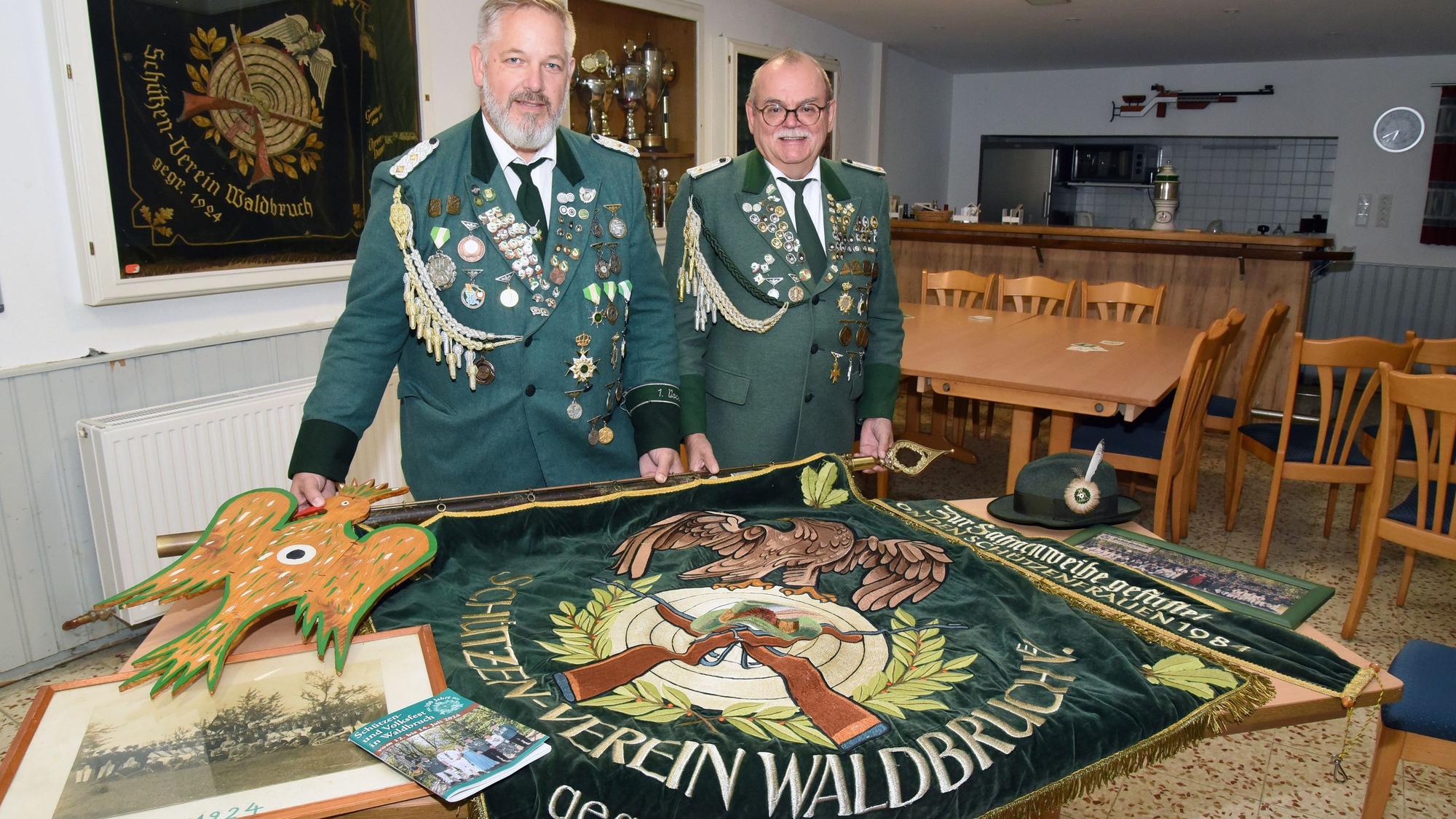 Schützenvorsitzender Magnus Brand (l.) und Kassierer Andreas Lobell stehen nebeneinander. Vor ihnen liegt die Vereinsfahne des Schützenvereins Waldbruch.