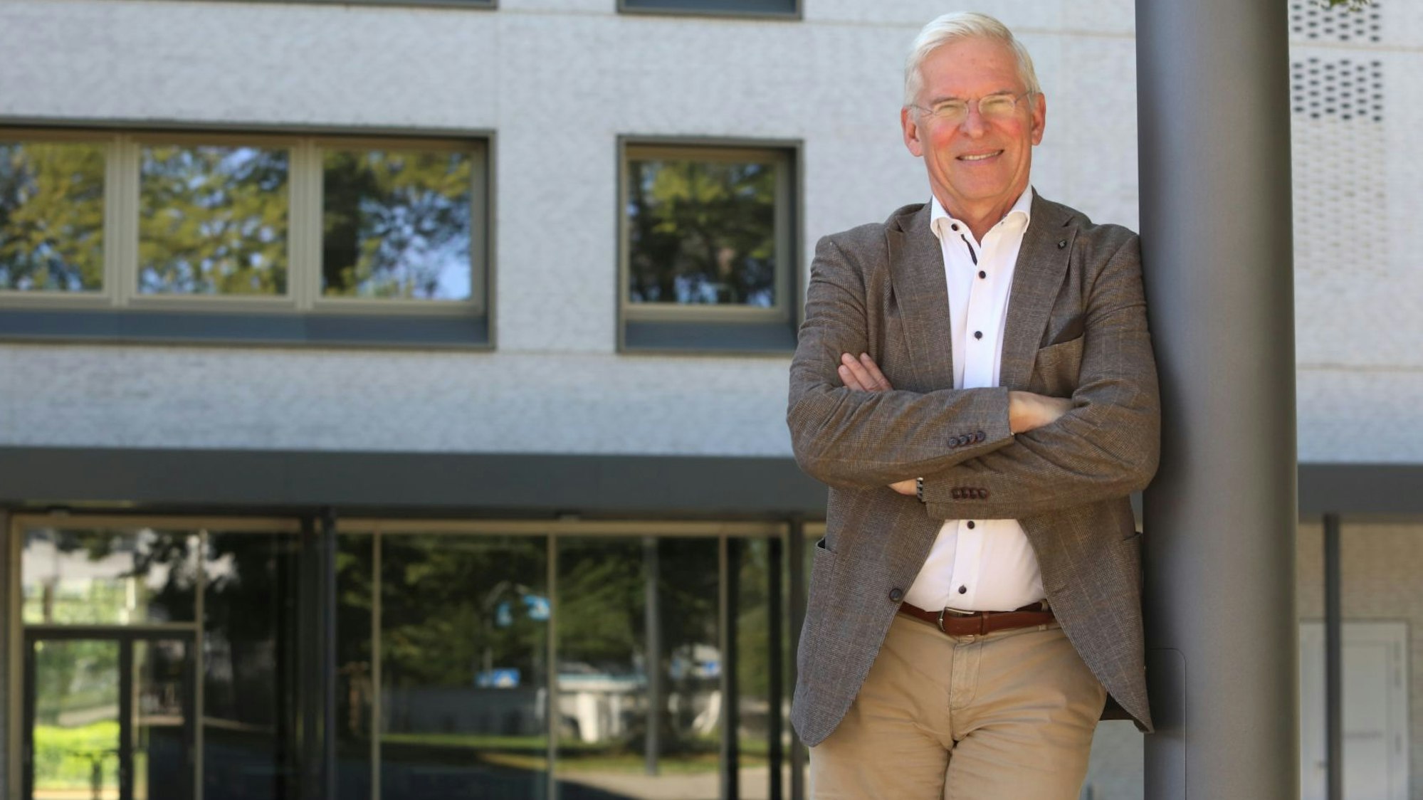 Ein Mann steht, an einen Mast gelehnt, vor der Bad Honnefer Schule.