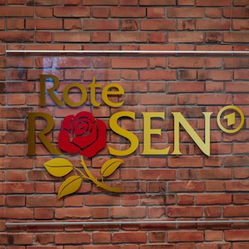 Das Logo der Telenovela "Rote Rosen" hängt im Studio an einer Wand.
