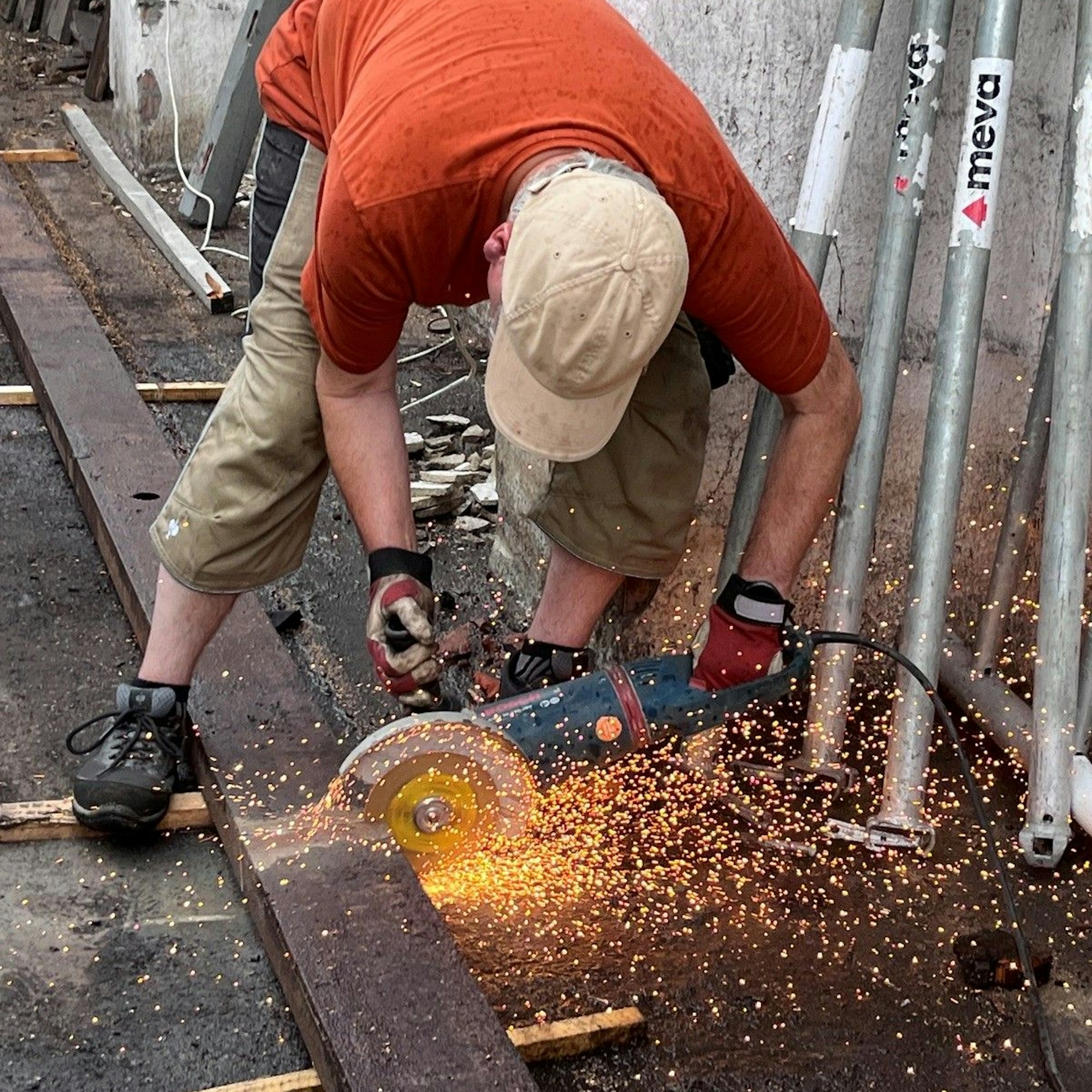 Ein Mann trennt Material mit einem Winkelschleifer, Funken fliegen.