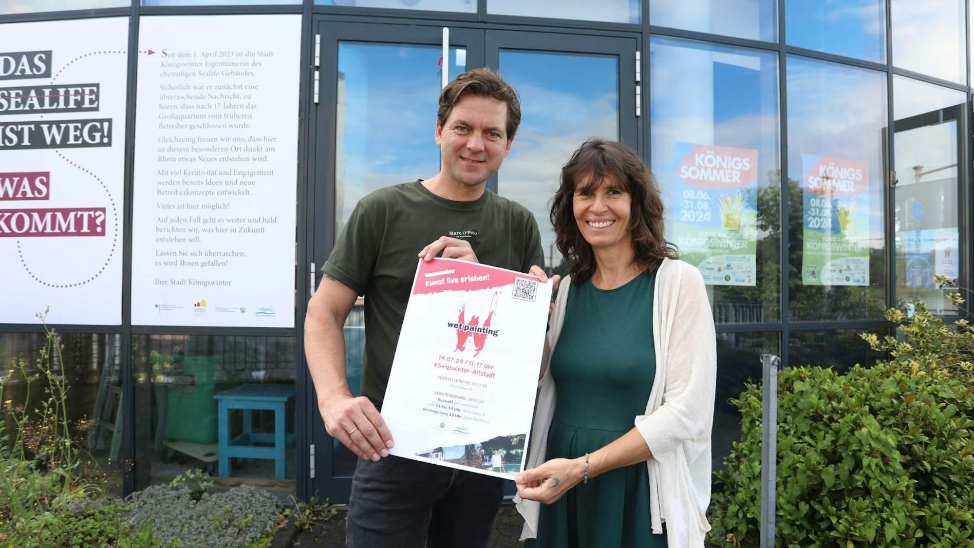 Ein Mann und eine Frau halten ein Plakat in den Händen.