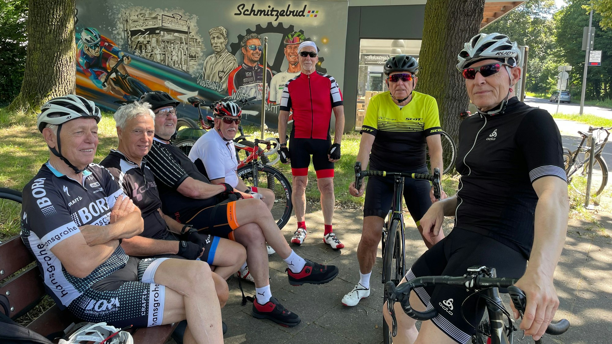 Zahlreiche Männer in Radfahrbekleidung vor der „Schmitzebud“.