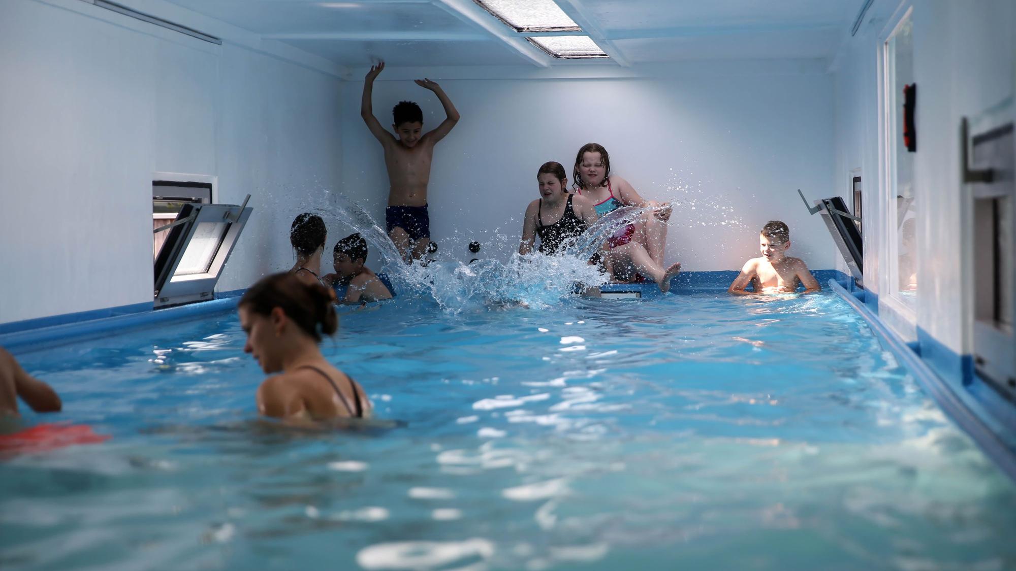 Kinder spielen im Wasser in einem Schwimmcontainer.