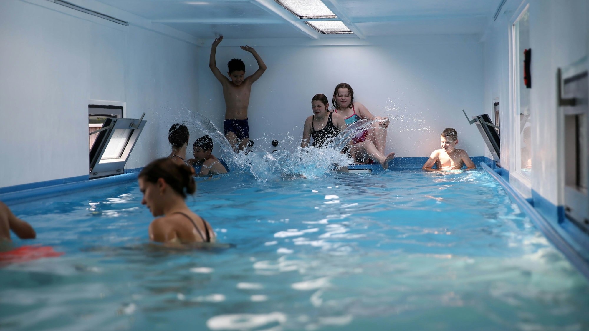 Kinder spielen im Wasser in einem Schwimmcontainer.