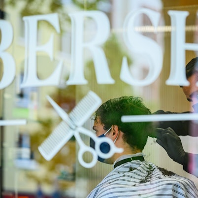 Ein Friseur schneidet in einm Barbershop einem Kunden die Haare.
