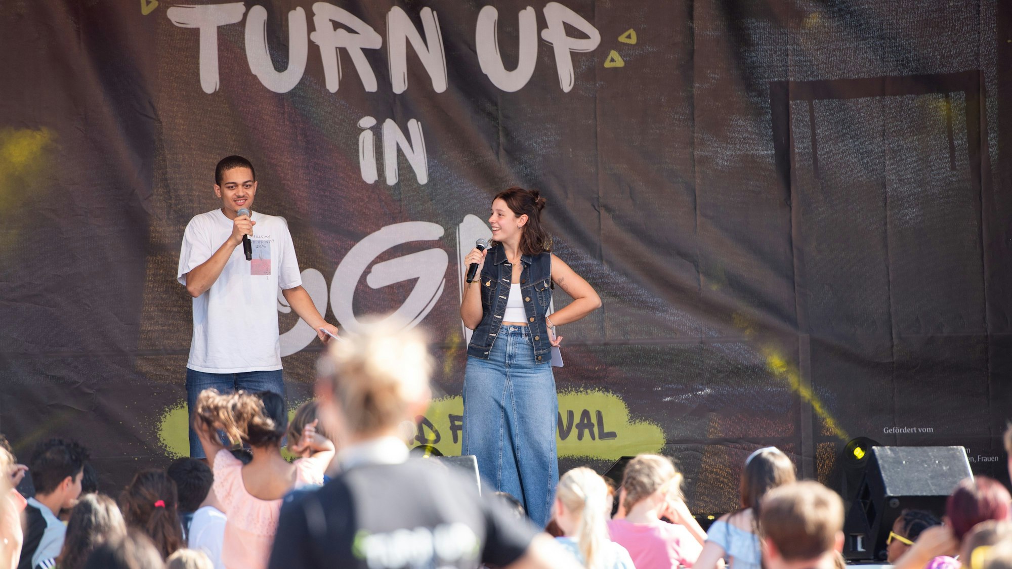 Zwei Jugendliche stehen auf einer Bühne,
