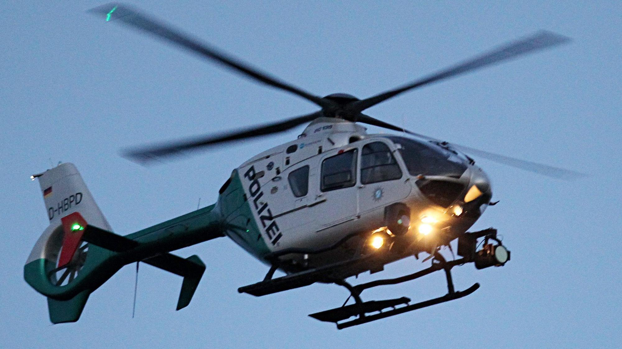Ein Polizeihubschrauber mit eingeschaltetem Suchscheinwerfer.