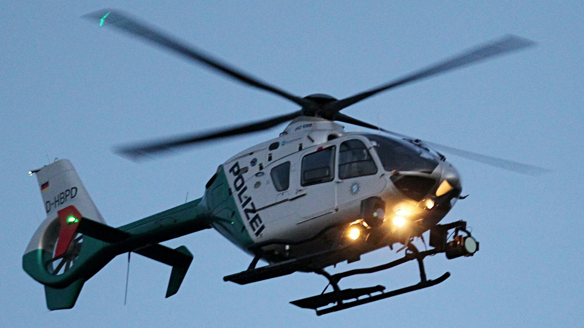 Ein Polizeihubschrauber mit eingeschalteten Scheinwerfern.
