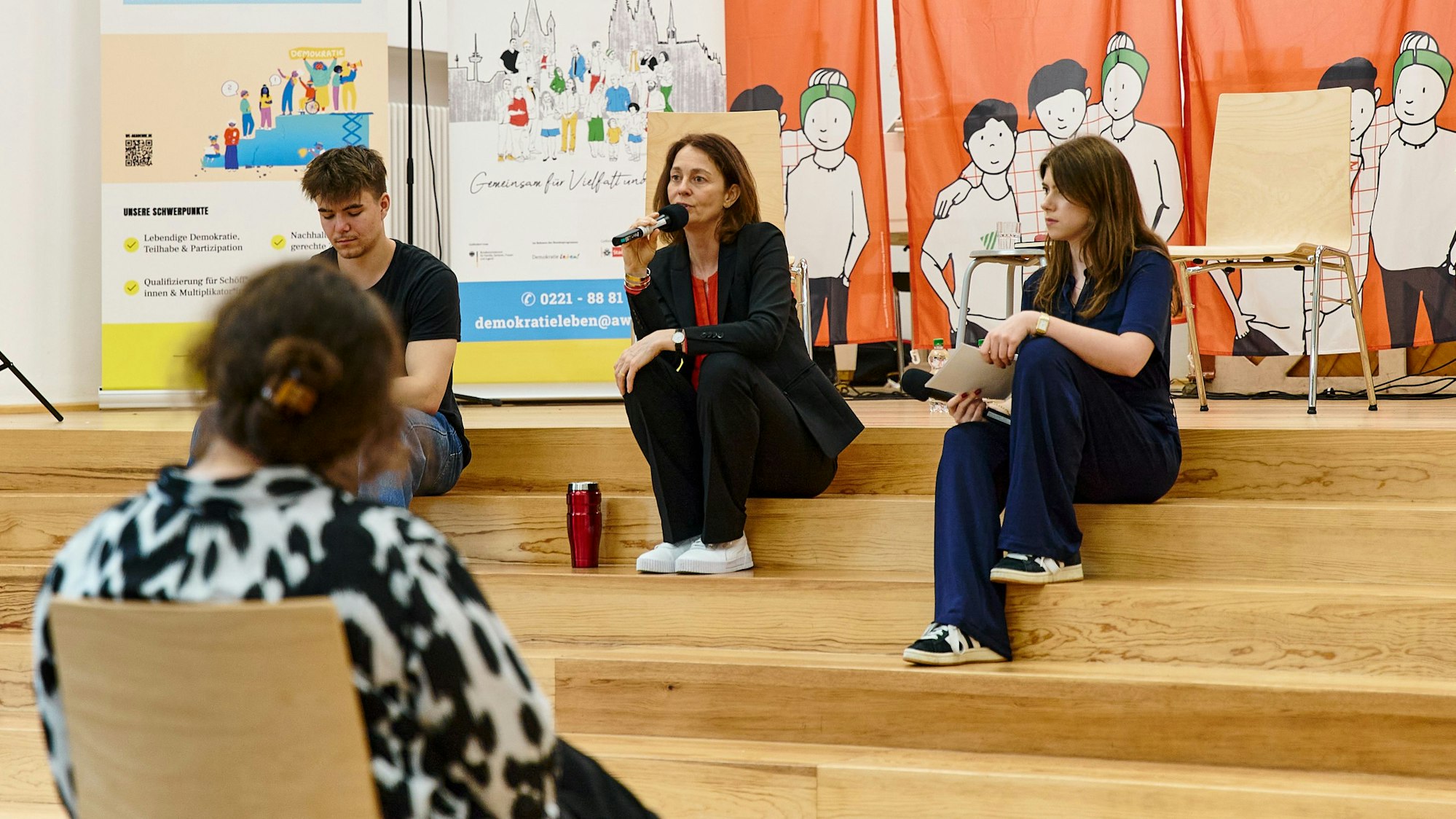 Katarina Barley und zwei Jugendliche sitzen auf einer Treppe.