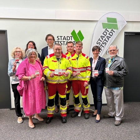 Menschen stehen nebeneinander und halten Karten in den Händen.