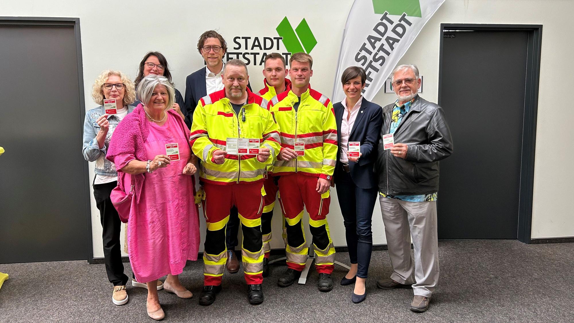 Menschen stehen nebeneinander und halten Karten in den Händen.