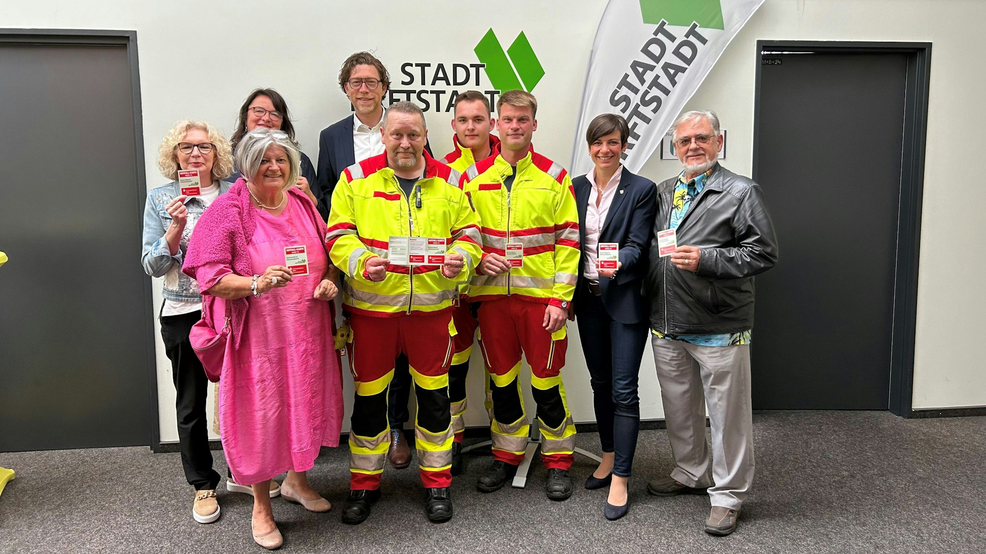 Menschen stehen nebeneinander und halten Karten in den Händen.