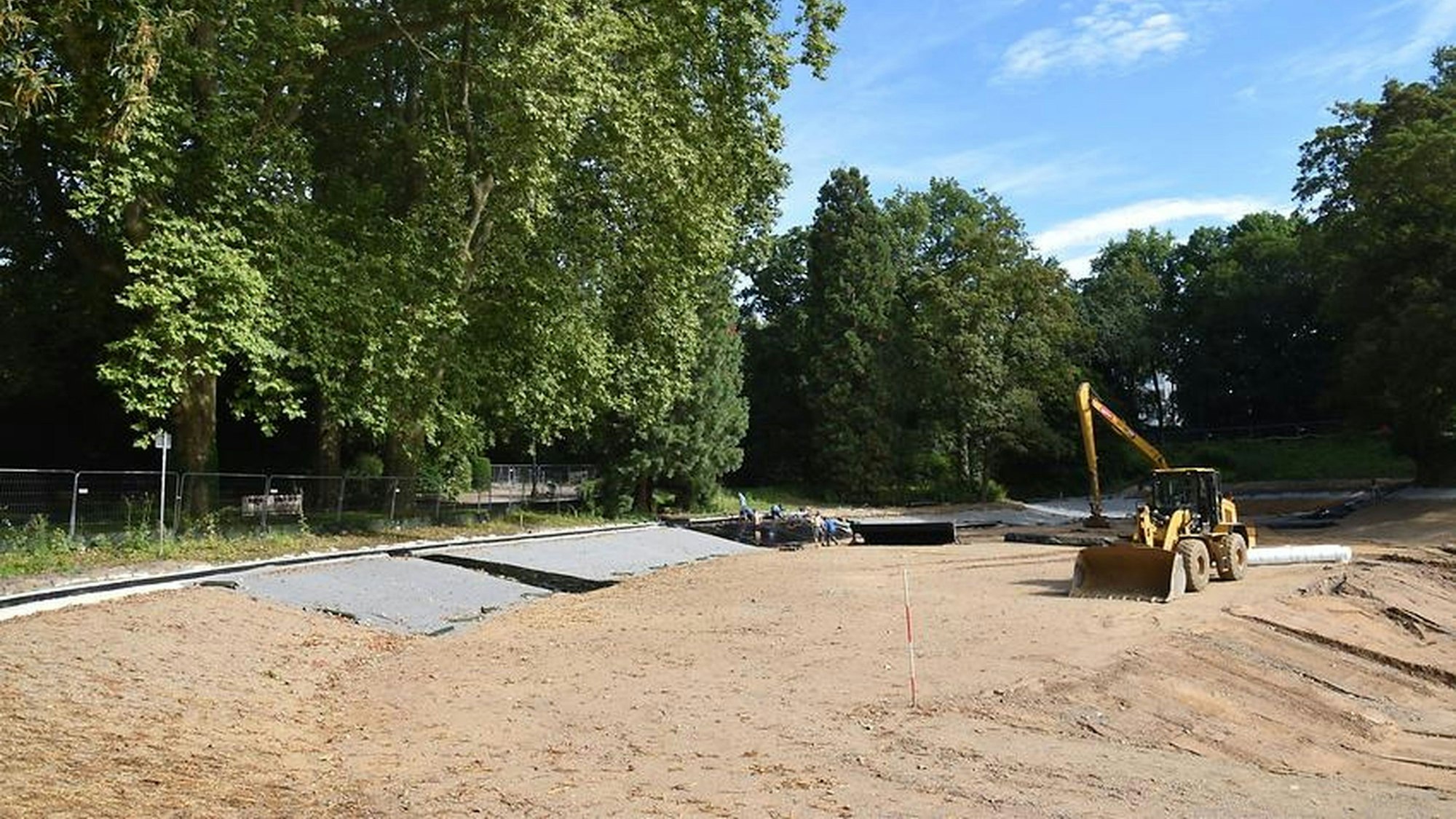 Ein Bagger planiert den neuen Untergrund im Weiher Volksgarten.