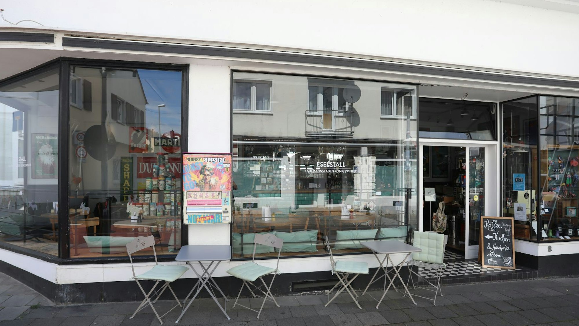 Ein kleines Lokal mit einer großen Fensterfront und Stühlen auf dem Gehweg.