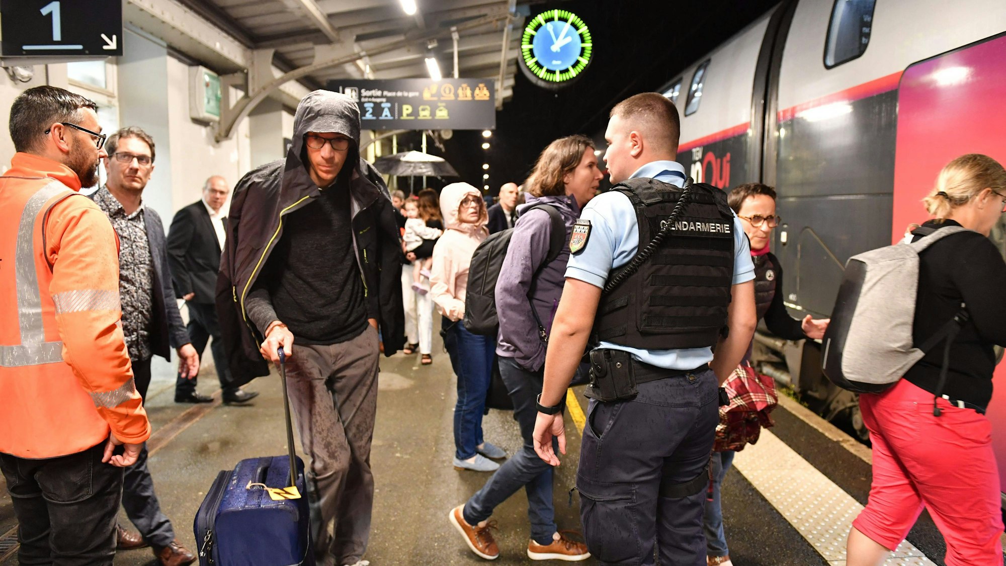 Passagiere und Passagierinnen stehen vor einem Zug.