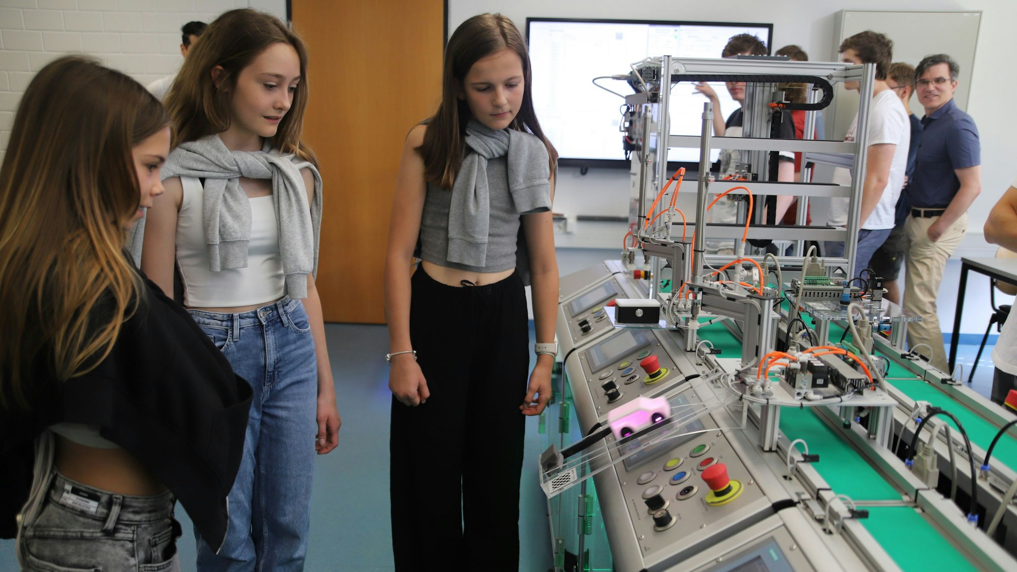 Drei Schülerinnen staunen über ein pinkes Auto.