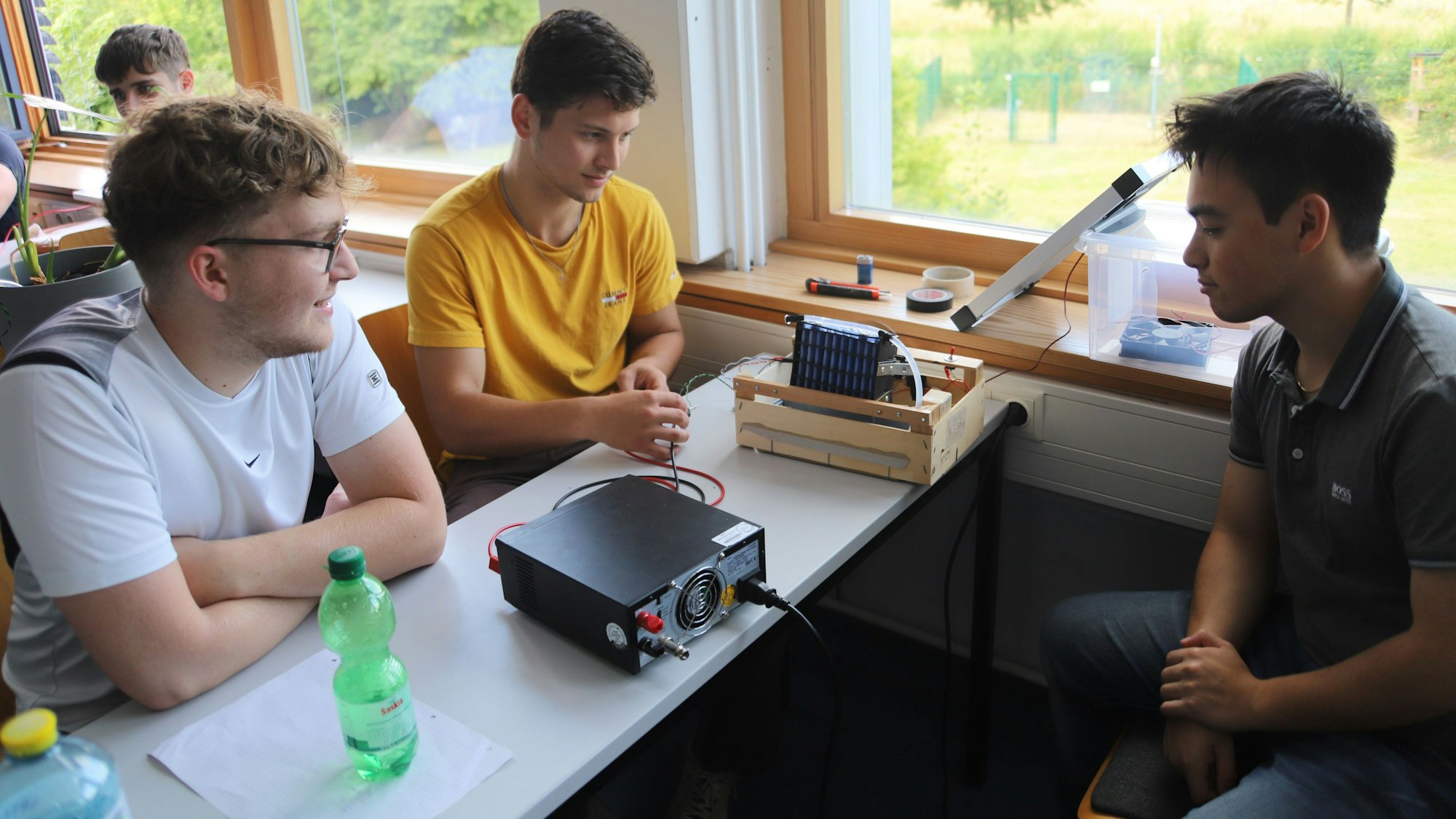 Drei Studierende zeigen ihren solarbetriebenen AirCooler.