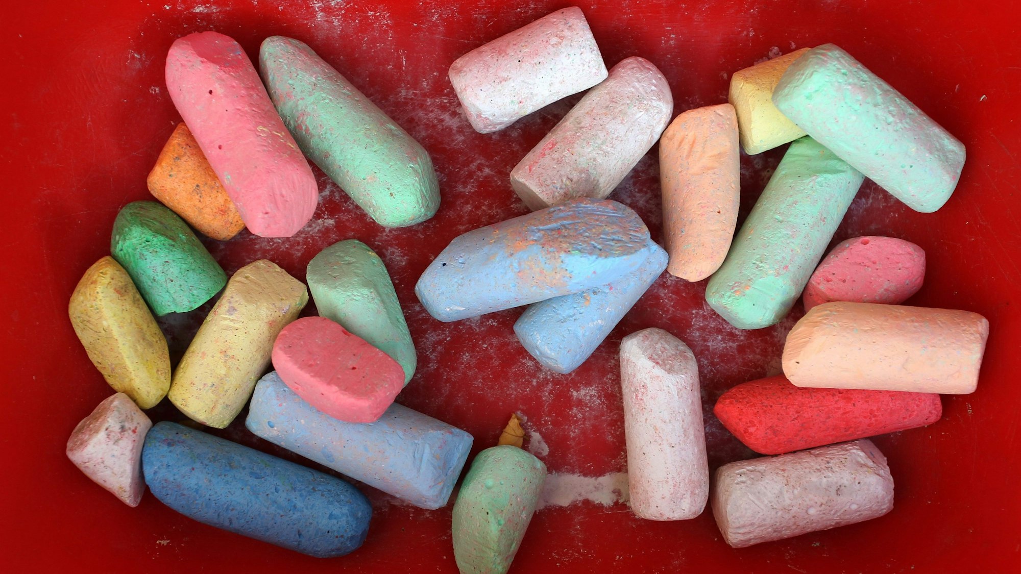 Bunte Straßenmalkreide liegt im Anhänger eines Bobby-Cars.