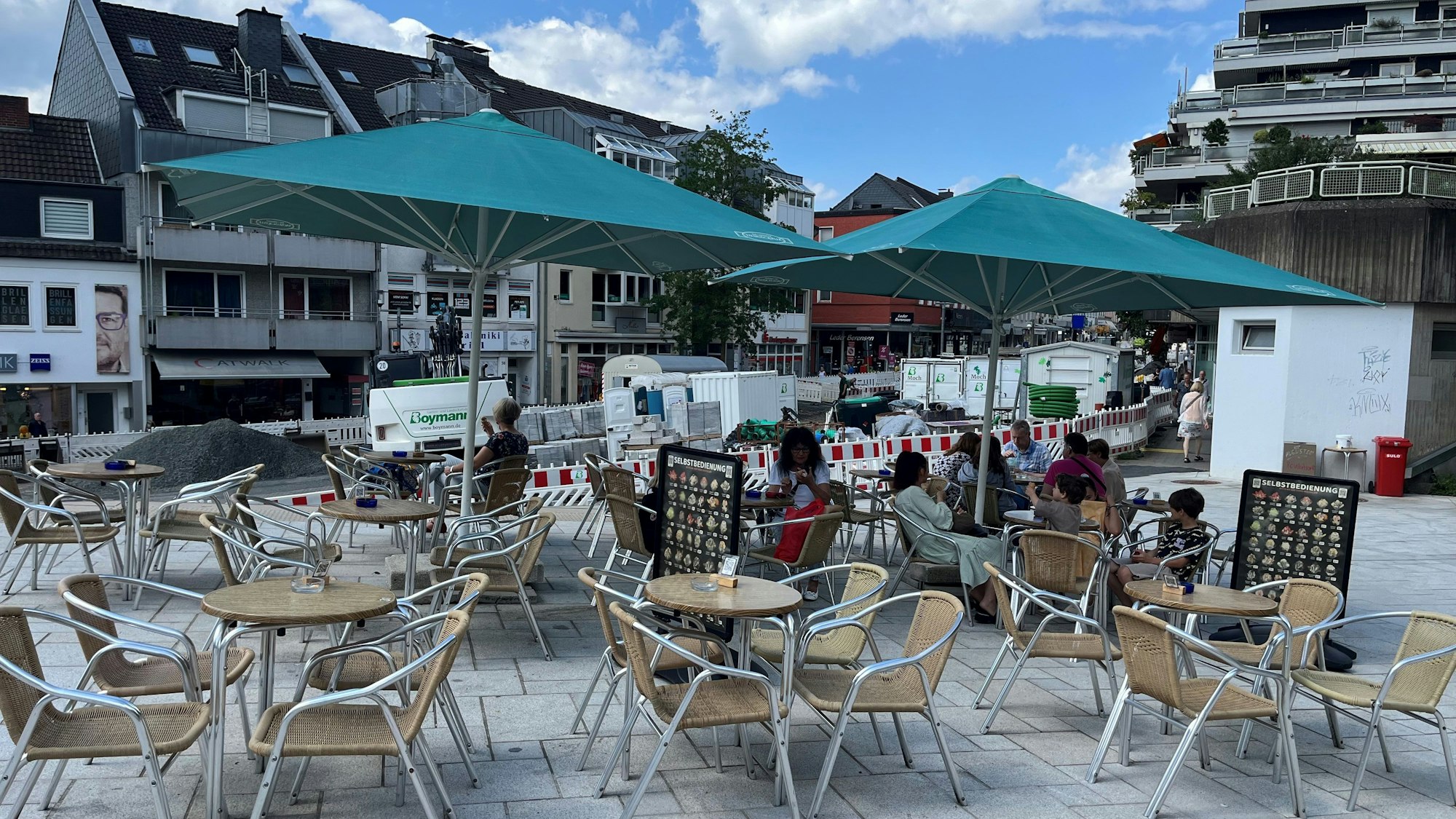 Tische und Stühle eines Eiscafés unter Sonnenschirmen.