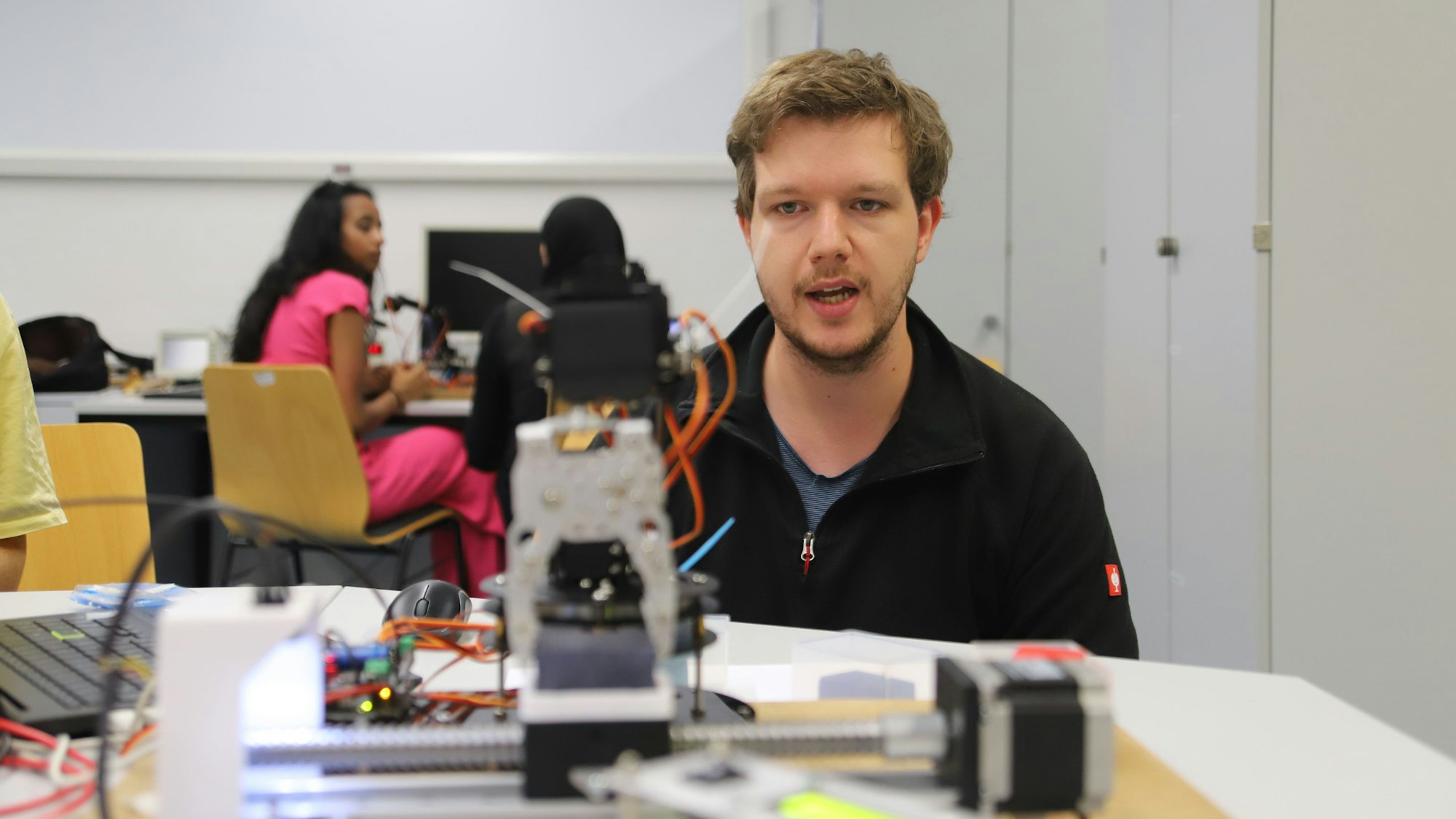 Ein Student beobachtet einen Greifroboter in Aktion.
