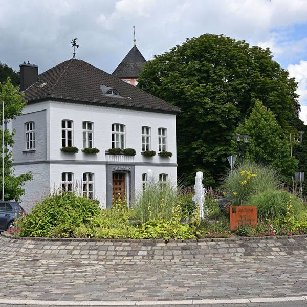 Der Kreisverkehr in Odenthal mit Springbrunnen und Blumen, dahinter das Rathaus.