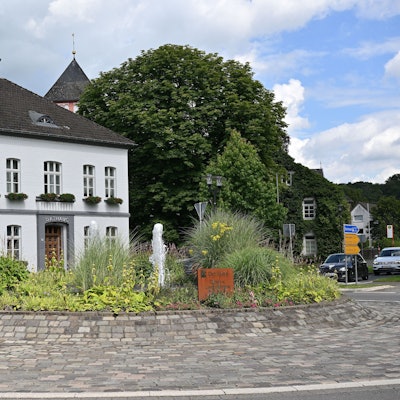 Der Kreisverkehr in Odenthal mit Springbrunnen und Blumen, dahinter das Rathaus.
