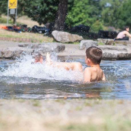 Das Bild zeigt zwei Kindern, die im Wasser plantschen.