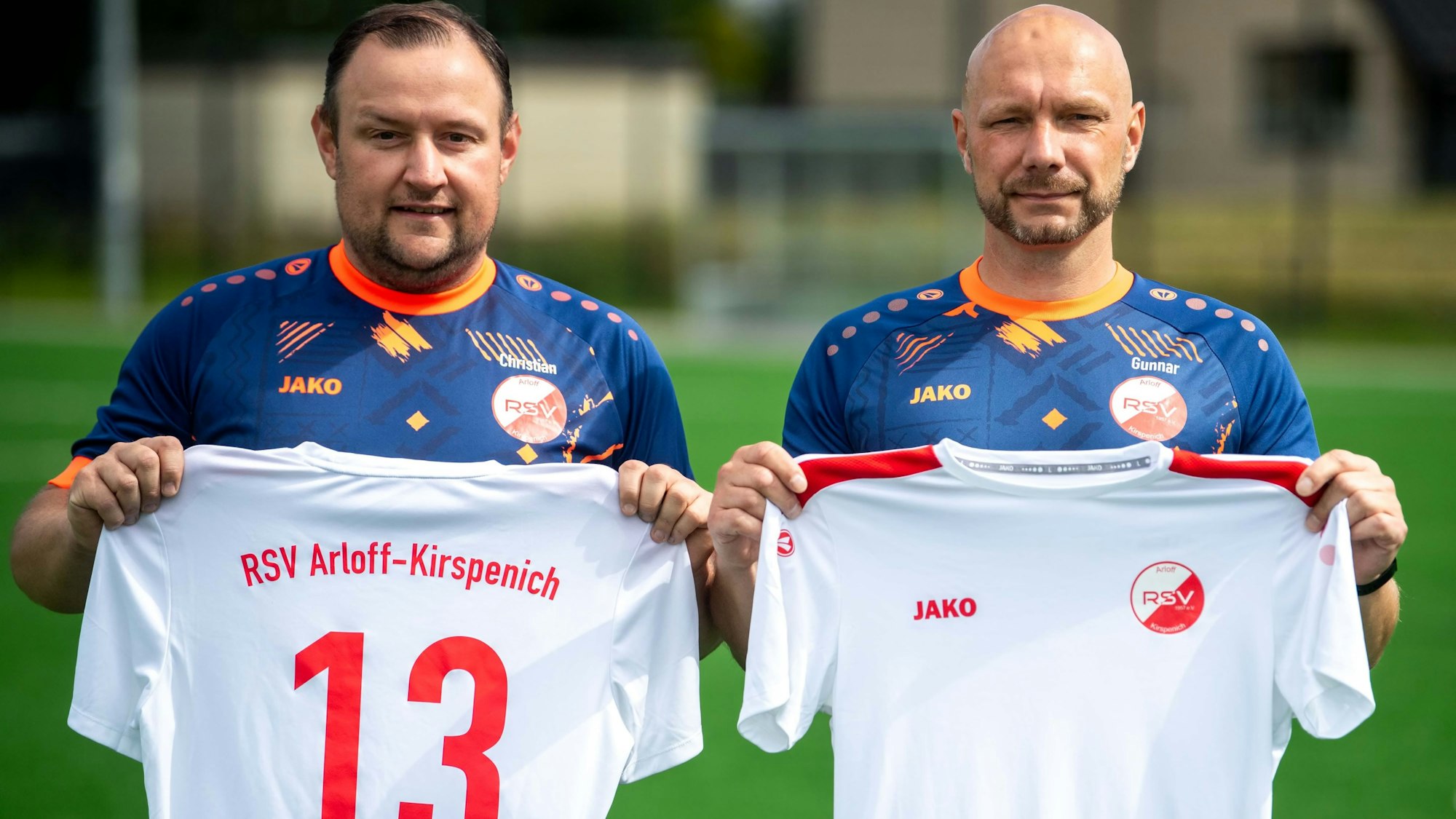Das Bild zeigt den Sportlichen Leiter und den Trainer des RSV Arloff-Kirspenich. Beide halten ein weißes Trikot in den Händen.