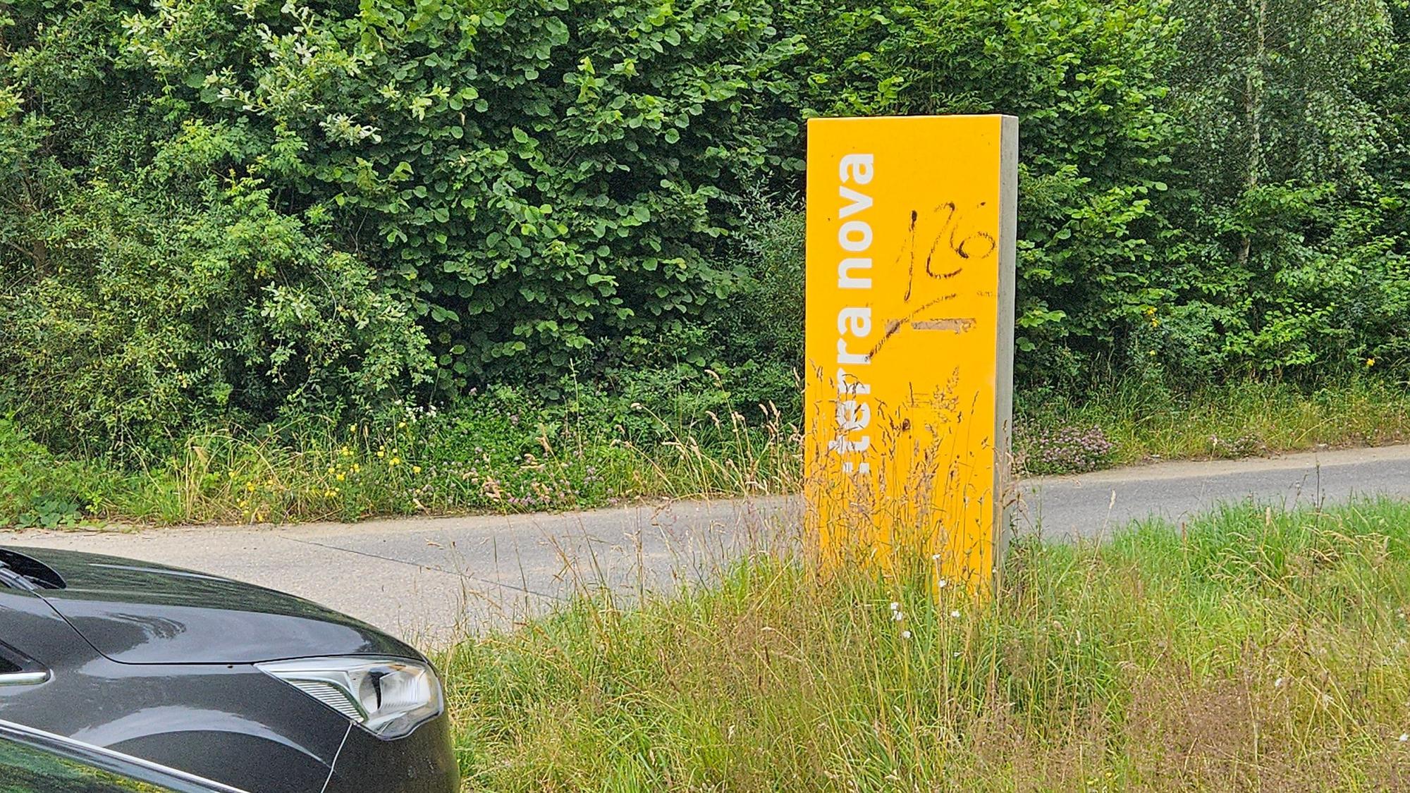 Zu sehen ist ein gelbes Schild an einem Weg.